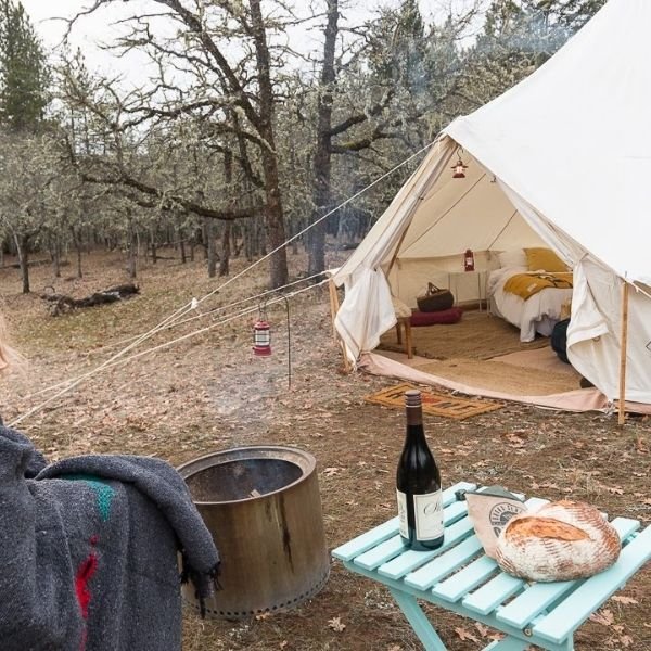 white canvas glamping tent with bonfire outside