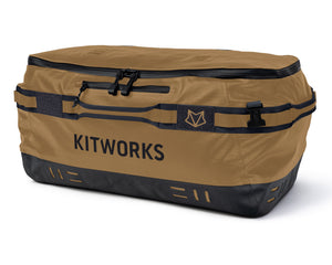 A Kitworks waterproof duffel bag in tan and black, featuring multiple zippered compartments, compression straps, and the Kitworks logo printed on the front, set against a plain white background.