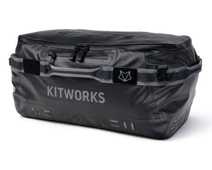 A dark gray waterproof duffel bag with 'KITWORKS' printed in white on the front, featuring a gray carrying strap with a black logo patch, set against a plain white background.