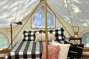 woman standing outside window of furnished bell tent