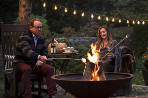 couple roasting marshmallows around fire pit