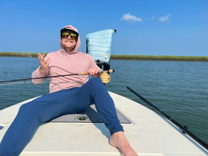 Person fishing on a boat with a clear blue sky and water background