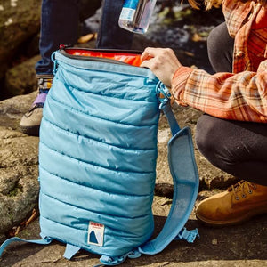 Person opening a blue cooler on a rocky ground