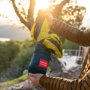 Person holding a backpack with 'Grand Trunk' logo against a natural background