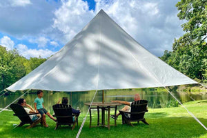 sun shade canopy with family under it near a lake