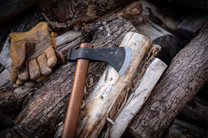 barebone field hatchet on logs near gloves