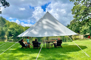 sun shade tent with people and a lake in the background