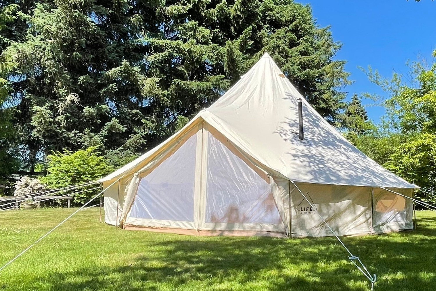 A clean bell tent in the sun on grass