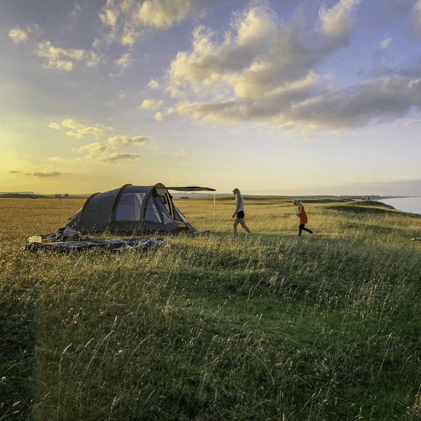 family camping tent in grass at sunset