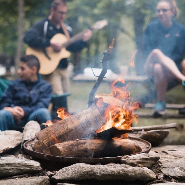 campers playing guitar and sitting by bonfire