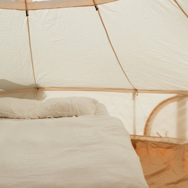 camp bed setup inside a white canvas bell tent