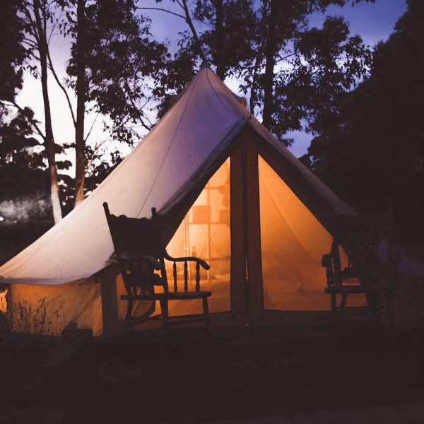 glowing canvas bell tent at dusk with rocking chair
