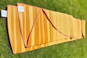 2 yellow striped outdoor rugs on grass