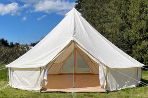 double door bell tent in a field by trees