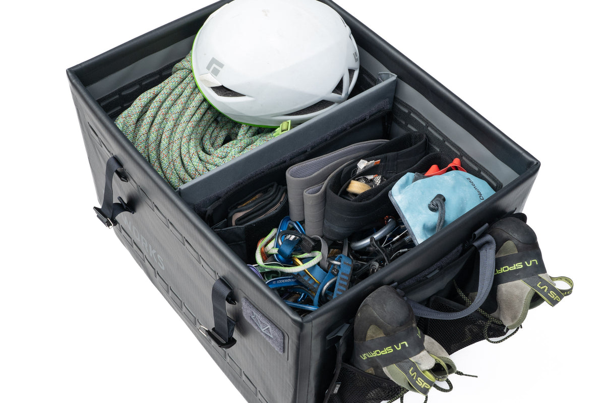Storage compartment with climbing gear including a helmet, ropes, and harnesses on a white background
