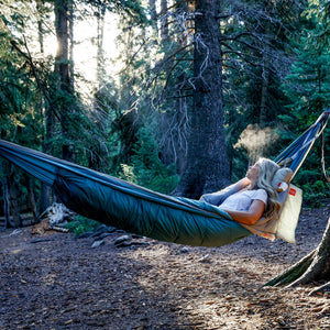 Person relaxing in a hammock in a forest setting
