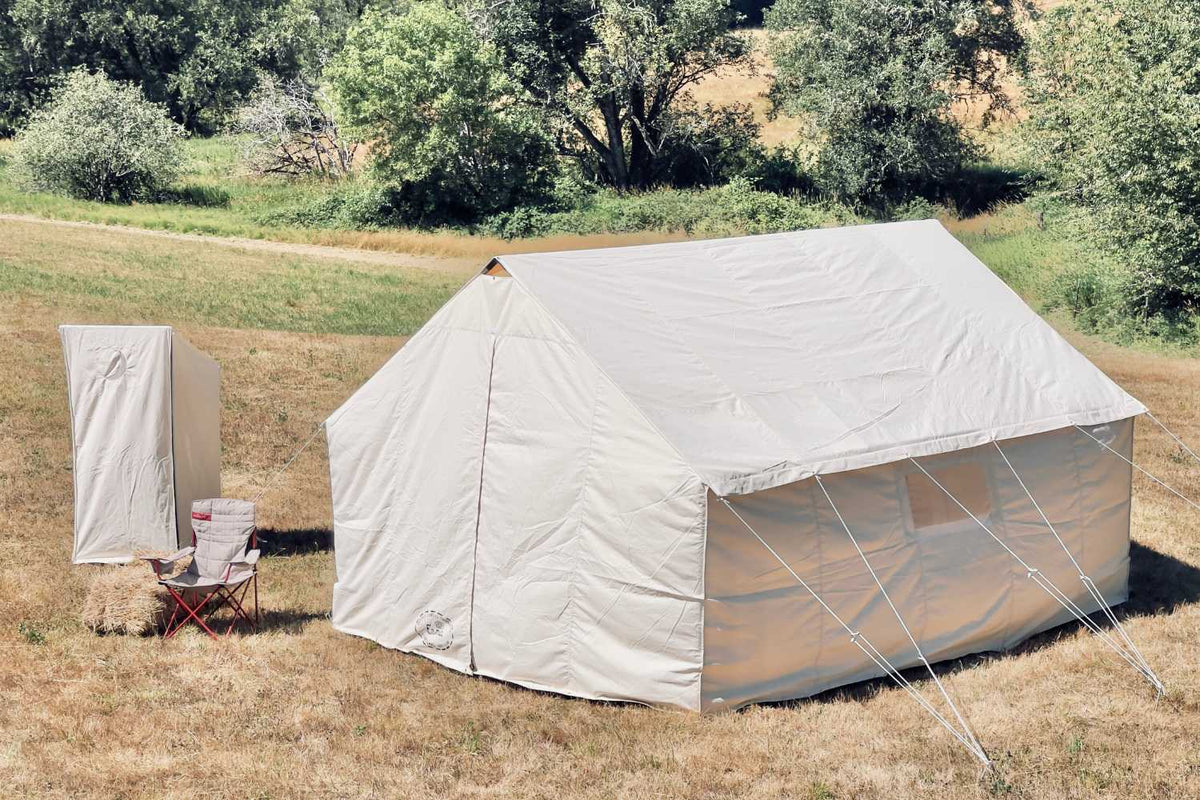 wall tent and canvas outhouse in a field