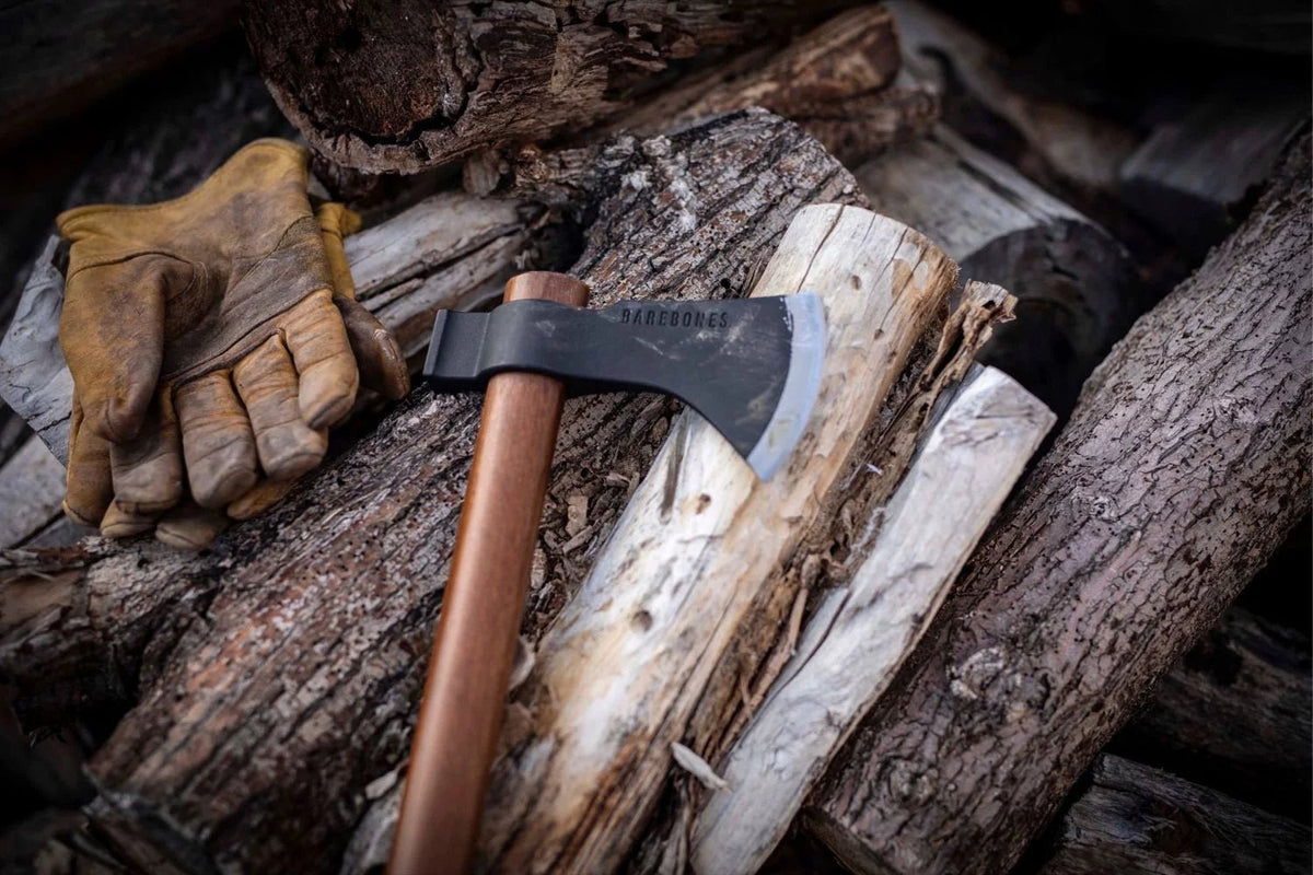 barebone field hatchet on logs near gloves
