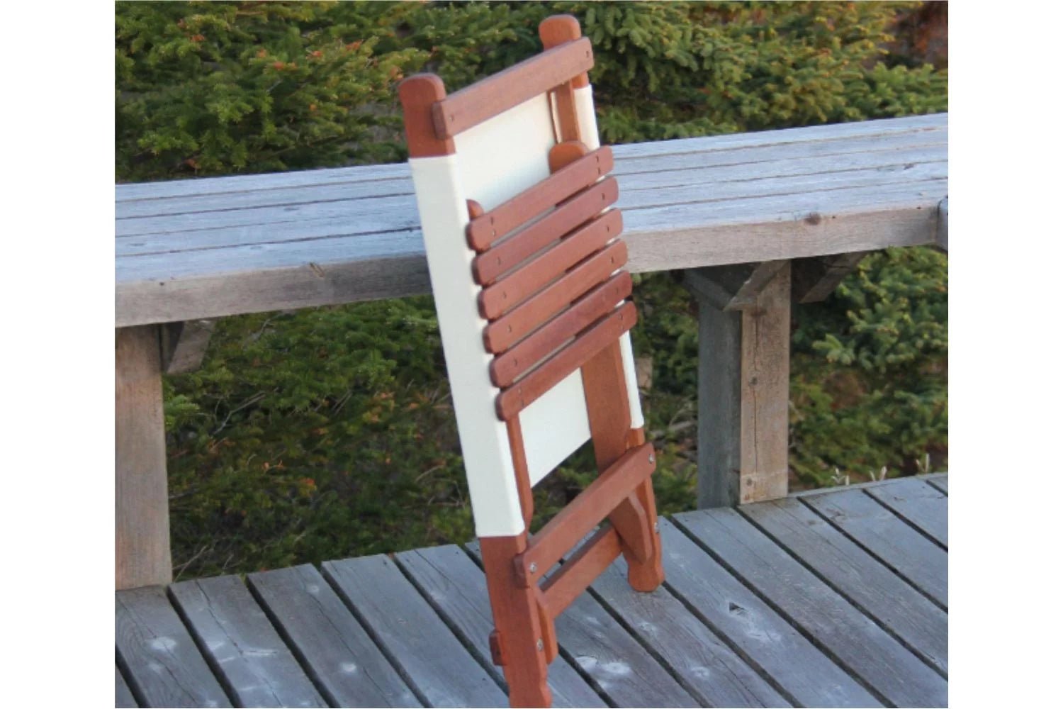 Wooden folding chair with green fabric back support and a matching small folding table on a deck.